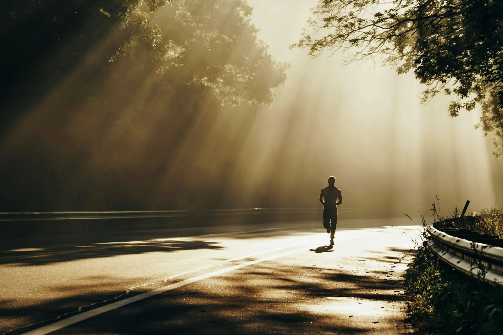 Runner on road with sunlight rays